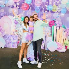 a man and woman pose for a photo in front of balloons, confetti and streamers