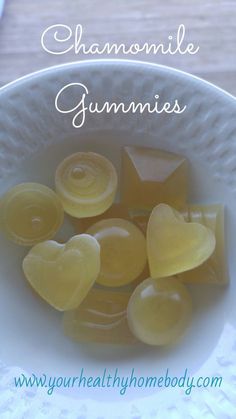 a white bowl filled with yellow gummies on top of a wooden table next to a plate