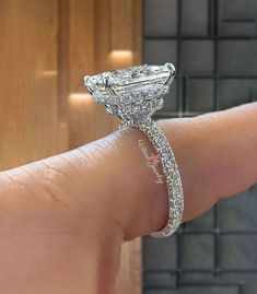 a close up of a person's hand with a diamond ring on their finger