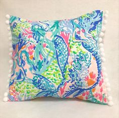 a colorful pillow with pom - poms on the bottom and an image of fish