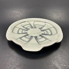 a white plate sitting on top of a black table next to a cup and saucer