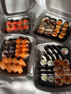 four trays filled with different types of sushi and other foods on top of a table