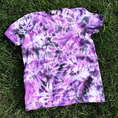 a purple and black tie dye shirt laying on the grass