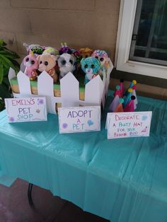 there are many stuffed animals on display at the table with their name tags in front of them