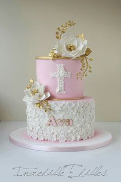 a pink and white cake with flowers on the top is decorated with gold leaf accents