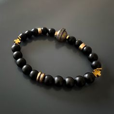 The Black Vibe Onyx Stone Beaded Gladiator Bracelet is more than just a piece of jewelry—it's a symbol of strength and confidence. The combination of black onyx stones and gold hematite beads creates a striking contrast that adds depth and dimension to the handmade bracelet. Black onyx is known for its protective qualities and is believed to absorb negative energy, while gold hematite is associated with grounding and stability. The gladiator charm serves as a reminder of the warrior within, symb Handmade Onyx Black Bracelets, Handmade Black Onyx Bracelets, Handmade Symbolic Black Beaded Bracelets, Handmade Symbolic Black Bracelets, Black Spiritual Hand-strung Jewelry, Luxury Black Hand-strung Beaded Bracelets, Handmade Black Spiritual Bracelet, Handmade Spiritual Black Bracelet, Black Symbolic Jewelry With 8mm Beads