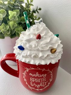 a red cup filled with whipped cream on top of a table next to a potted plant