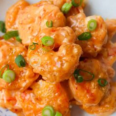 a white plate topped with meat covered in sauce and green onions next to broccoli