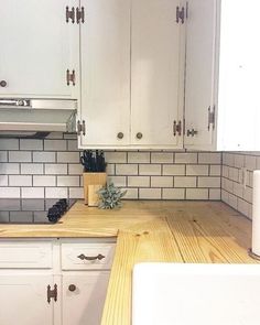 a kitchen with white cabinets and wood counter tops in front of a stove top oven