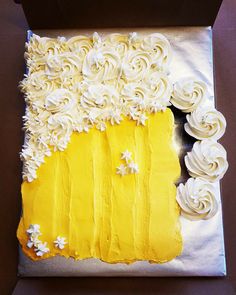 a cake with white frosting and yellow icing in a box on a table