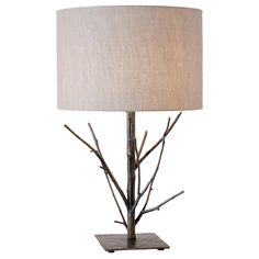 a table lamp with branches on it and a white shade over the light, against a white background