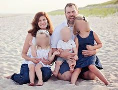 a man and two women are sitting on the beach with their babies in front of them