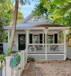 a small white house surrounded by trees and leaves