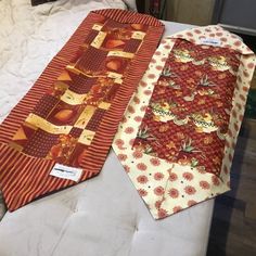 two ties are laying next to each other on a bed