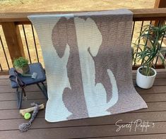 a blanket sitting on top of a wooden deck next to a potted plant