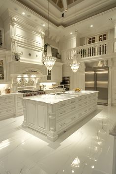 a large white kitchen with an island in the middle and chandeliers hanging from the ceiling