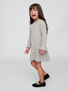 Supersoft ribbed knit sweater dress.  Crewneck.  Long sleeves with ruffle cuffs.  Godet styling at skirt.  This product was made in a factory that runs the Gap Inc.  P. A. C. E.  Personal Advancement & Career Enhancement) program.  P. A. C. E.  is our educational program that helps the women who make our clothes build the skills, knowledge, confidence & resilience needed to advance in work & life.  Learn more here.  Fit and flare silhouette.  Hits at the knee.  Sizes range from baby to toddler. Gray Sweater Dress, Girls Designer Dresses, Kids Robes, Rib Sweater, Knitted Design, Jersey Knit Dress, Ribbed Sweater Dress, Kids Designer Dresses, Dress Pleated