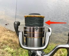 a fishing rod is attached to the handlebars of a spinning reel with an arrow pointing at it