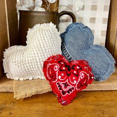 three heart shaped pillows sitting on top of a wooden shelf