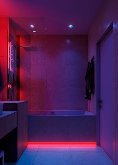 a bathroom with red and blue lights on the wall, tub and sink in the foreground