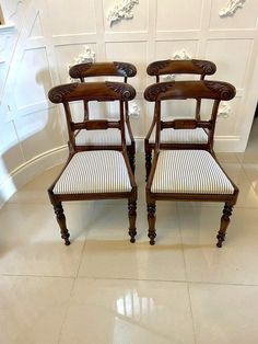 two wooden chairs sitting next to each other on top of a tiled floor in front of white walls