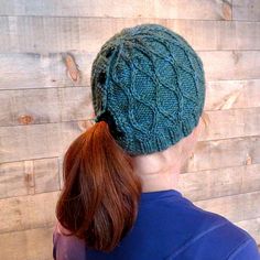 a woman with red hair wearing a green knitted hat