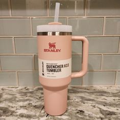 a pink tumbler cup with a straw in it sitting on top of a counter