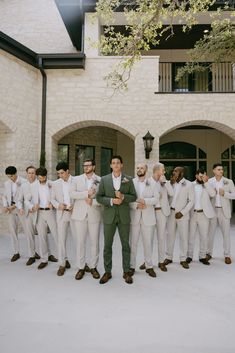 a group of men standing next to each other in front of a white brick building