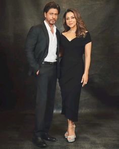 two people standing next to each other in front of a black background wearing formal clothes