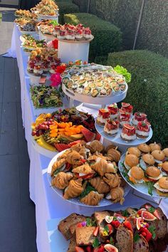 a long table filled with lots of different types of sandwiches and pastries on plates