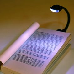 an open book sitting on top of a table next to a lit up light bulb