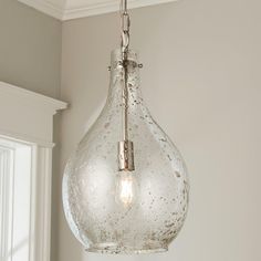 a glass light fixture hanging from a ceiling in a room with white walls and windows