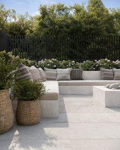 an outdoor seating area with plants and pillows