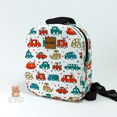 a lunch bag with cars on it and a black ribbon around the strap, sitting against a white background