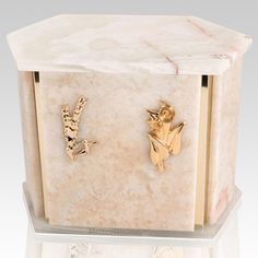 a white marble box with two gold angel charms