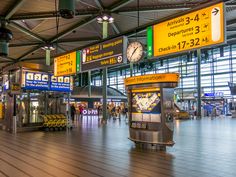 the inside of an airport terminal with many signs and luggage carousels in the background