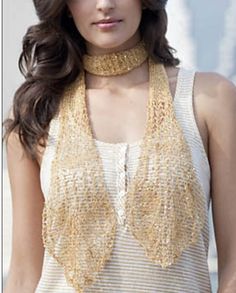 a woman with long hair wearing a white top and gold necklace on her neck, standing in front of a wall