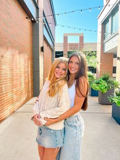 two young women are hugging each other outside