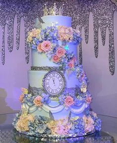 a three tiered cake decorated with flowers and a clock