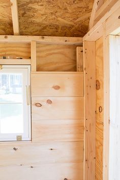 the inside of a small cabin with wood paneling on the walls and windows in it