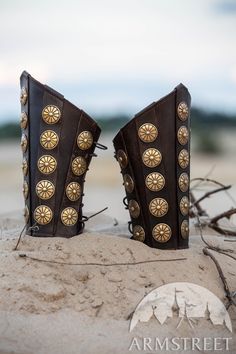 two brown boots with gold studs on them sitting in the sand