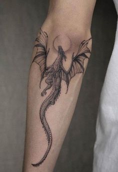 a black and grey dragon tattoo on the arm