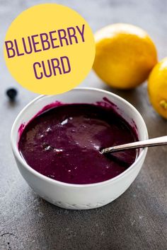 a white bowl filled with blueberry curd next to lemons