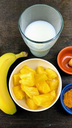 bananas, oranges, and other ingredients are on the table next to a glass of milk