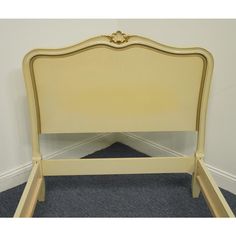 a yellow bed frame with an ornate headboard and foot board on carpeted floor