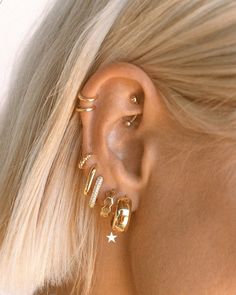 a woman with blonde hair wearing gold ear cuffs and piercings on her left ear