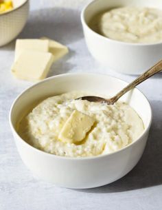 two white bowls filled with mashed potatoes and butter next to some slices of cheese