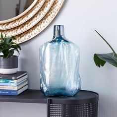 a blue vase sitting on top of a black shelf next to a potted plant