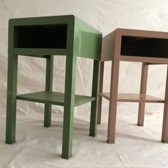 three different colored tables sitting next to each other on a white sheeted surface in front of a wall