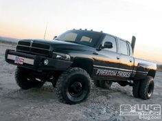 a black truck parked on top of a sandy beach